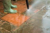 A pressure washer cleaning mildew off of a brick patio.