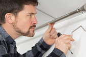 man installing a bracket support for a curtain rod