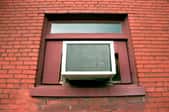 A window air conditioning unit installed in the window of a brick building.