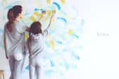 woman and girl painting a wall with two colors