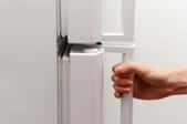 A hand on a white fridge door handle.