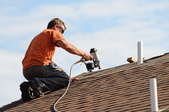 A man nails down a new roof.
