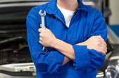 mechanic holding wrench in front of a car