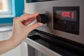 hand adjusting temperature knob on oven