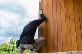 man installing pine lumber home siding