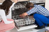 man and woman working on a dishwasher