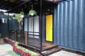 A tiny home with a yellow door made out of a shipping container. 
