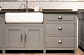 A gray kitchen cabinet with a white sink. 