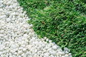 An area of white pea gravel meets the grass.