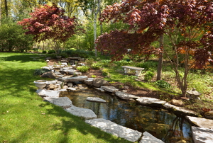A backyard pond edges with natural stone slabs.