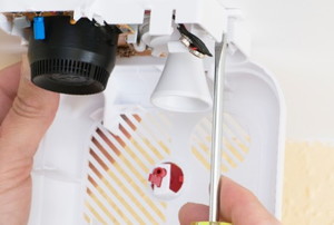 hands changing the battery of a smoke detector