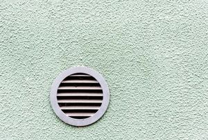 A vent in an exterior stucco wall.