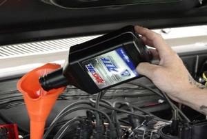 Pouring transmission fluid into an orange funnel.