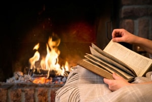 Someone reading a book by the fire. 