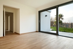 A sliding glass door leading from an empty apartment into the backyard.
