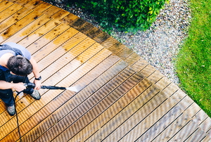 man washing deck with a pressure washer