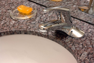 a corian countertop with a sink and a a glass cup with orange soap inside