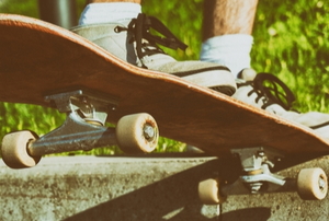 feet in sneakers riding a homemade skateboard on a sidewalk curb