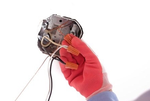 gloved hand working with wires in ceiling light fixture