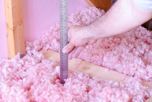 Loose fill insulation being measured with a ruler. 
