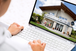 person looking at house on laptop