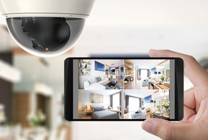 hand near security camera holding a phone with video feeds from home security system