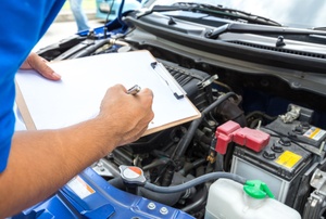 A man looks under the hood of a car.