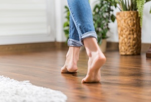 A wood laminate floor with someone walking on it.