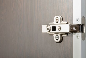a metal euro hinge on a door with Phillips head screws