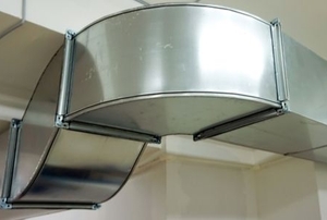a large, metal heating duct curving in a corner shape on the ceiling