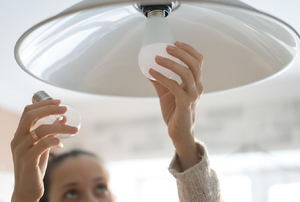 A woman installs a light bulb.