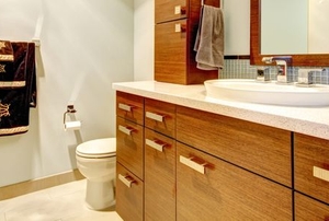 A bathroom vanity with wood cabinets next to toilet and towels
