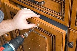 Cabinet Worker Drilling Hole for a new Drawer Pull Handle