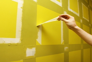 A man paints on a painted wall.