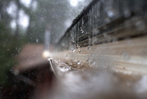 A close-up of rain falling into a gutter on a house.