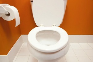 A toilet in an orange room.