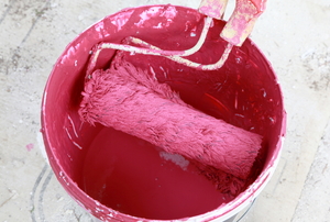 used paint roller in bucket of pink paint