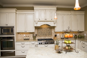 A fruit stand on an island in a kitchen with white cabinets.
