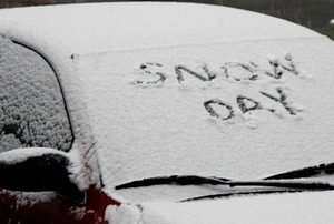 A car, buried in snow, with "Snow Day" written on the window.