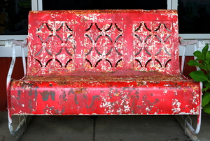 A red, rusty antique bench. 