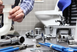 Person in a bathroom with variety of plumbing supplies