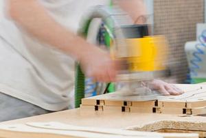 A woodworker using a router to cut MDF.