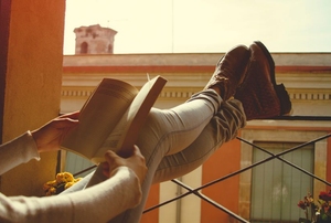 girl reclining on porch while reading book