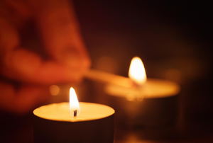 A close-up of two candles being lit. 