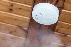 Smoke alarm mounted to a wood ceiling.