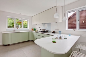 Large kitchen with light green cabinets and white countertops.