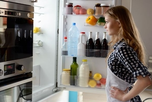 A woman standing in front of an open refrigerator.