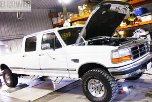 White Ford truck with hood up in a shop