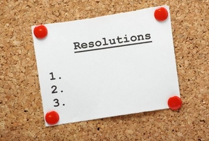 A white card with the word "Resolutions" on it thumb tacked to a cork board.