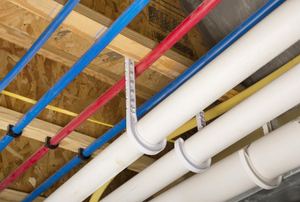 Plastic pipes hanging from an unfinished ceiling.